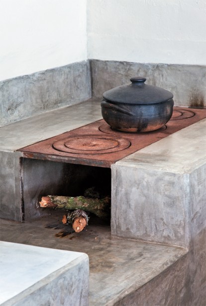 A bancada da pia e o revestimento do fog&atilde;o a lenha foram moldados na obra com cimento estrutural e impermeabilizados depois de prontos com tr&ecirc;s dem&atilde;os de resina &agrave; base de &aacute;gua. Nas paredes, o embo&ccedil;o r&uacute;stico recebeu acabamento de tinta acr&iacute;lica. Projeto Ricardo Hachiya e Luiza Fernandes.