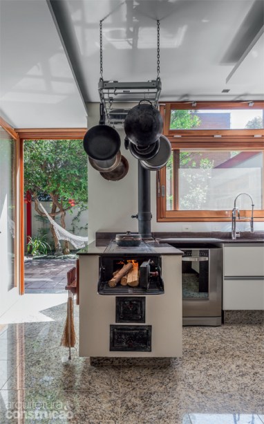 Sonho de consumo da moradora, a cozinha naturalmente clara foi muito bem equipada. Ganhou status de ambiente de convivência, aberta ao terraço e à sala de estar. Repare no fogão a lenha: da Ofcina Victorello, tem partes pré-moldadas de concreto e outras de ferro. Projeto da arquiteta Cristina Xavier.