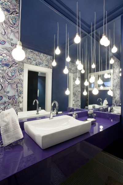 Feito para a mostra Morar Mais Bras&iacute;lia. este projeto de Ricardo Meira usa muitos recursos: papel de parede estampado, bancada roxa, teto azul e muitas lumin&aacute;rias que d&atilde;o um efeito de profundidade com o espelho.