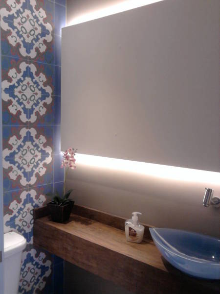 A arquiteta Andrea Del Monaco optou pela cerâmica hidráulica nos tons de branco, vermelho, azul e verde oliva para combinar com os demais elementos deste banheiro residencial, como o porcelanato de cimento queimado e a cuba azul de resina. A ideia é trazer sofistição, aliando elementos mais rústicos e que harmonizam com a iluminação indireta do painel. As placas de cerâmica têm 19,6 x 19,6 cm e foram fornecidas pela Antigua.