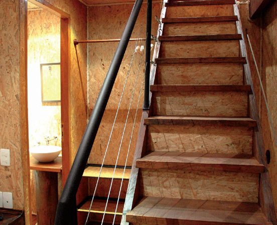 Placas de OSB ficam &agrave; mostra nas paredes e na escada, protegidas com um vern...