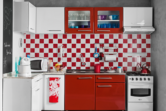 Comprados prontos, os armários respondem pela explosão de vermelho que vestiu esta cozinha quadrada. Mas não foi só o colorido que pesou na decisão. “Os modelos de aço têm bom preço e são duráveis”, argumenta Beatriz. A facilidade de limpeza é outro ponto positivo. Bastam pano úmido e sabão neutro para deixar as superfícies sempre brilhando. “Só mantenha-as longe de esponja de aço, álcool, saponáceos, sal e vinagre”, orienta o atendimento ao consumidor do fabricante, a Bertolini. E anote a dica de ouro: aplicar cera automotiva líquida com silicone a cada 90 dias forma uma película protetora sobre o metal. A combinação dos módulos foi pensada de modo a deixar nichos na medida certa para os eletrodomésticos. Assim, o efeito fica semelhante ao conquistado com mobiliário planejado. Com tinta esmalte na cor grafite obteve-se um mural de recados prático e charmoso na parede lateral. Já o aspecto de cimento queimado resulta de textura lisa – as ranhuradas juntam sujeira e gordura, por isso, são proibidas nesse tipo de ambiente.