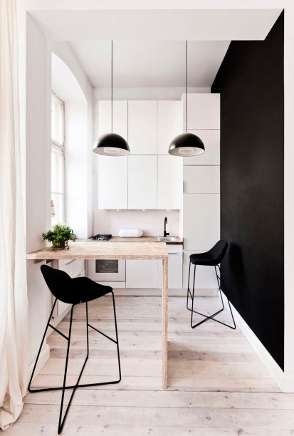 &Eacute; dif&iacute;cil pensar em maneiras de valorizar a cozinha em um apartamento de apenas 29 metros quadrados. Mas &eacute; poss&iacute;vel faz&ecirc;-lo! Min&uacute;scula, esta ocupa uma parede e meia com arm&aacute;rios brancos que deixam o ambiente mais iluminado e com uma sensa&ccedil;&atilde;o de amplitude aumentada. Uma bancada de madeira super texturizada ainda serve de mesa de jantar.