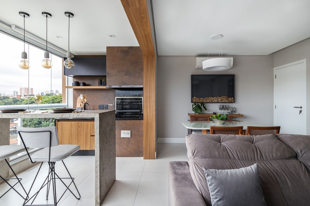 Porcelanato que imita aço corten emoldura churrasqueira em apê de 80 m²