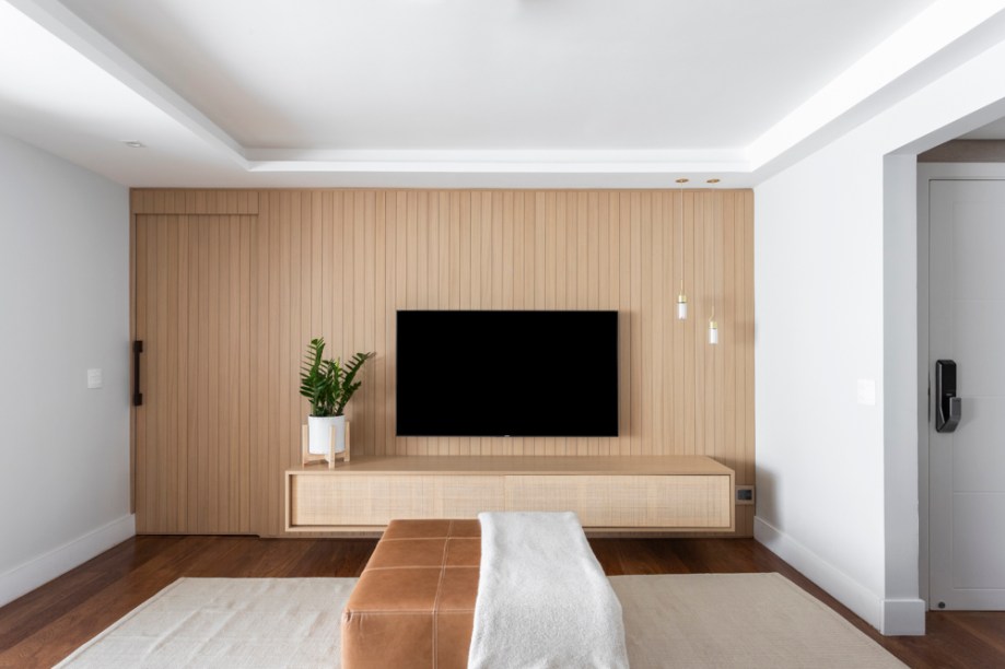 O painel da TV, produzido com ripas verticais de Carvalho Americano, agregou textura à parede, além de camuflar a porta de correr