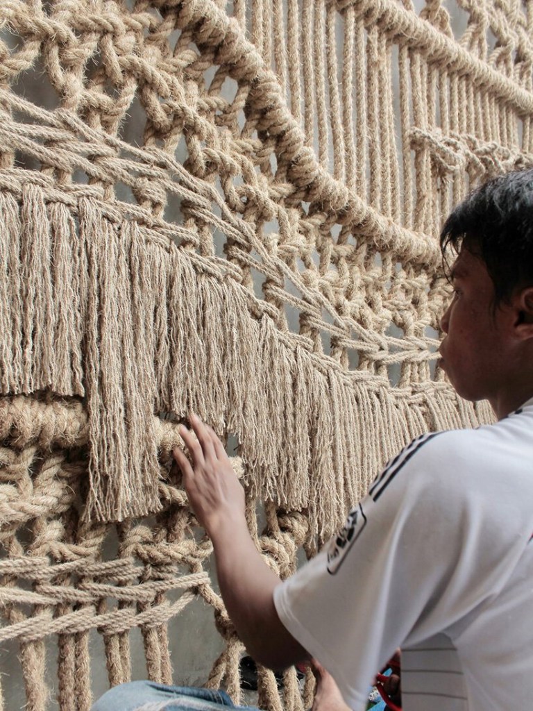 Homem mexendo no macramê da obra