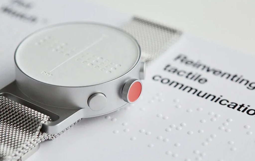 Detalhe do mostrador do Dot watch. Com manual em braille na mesa