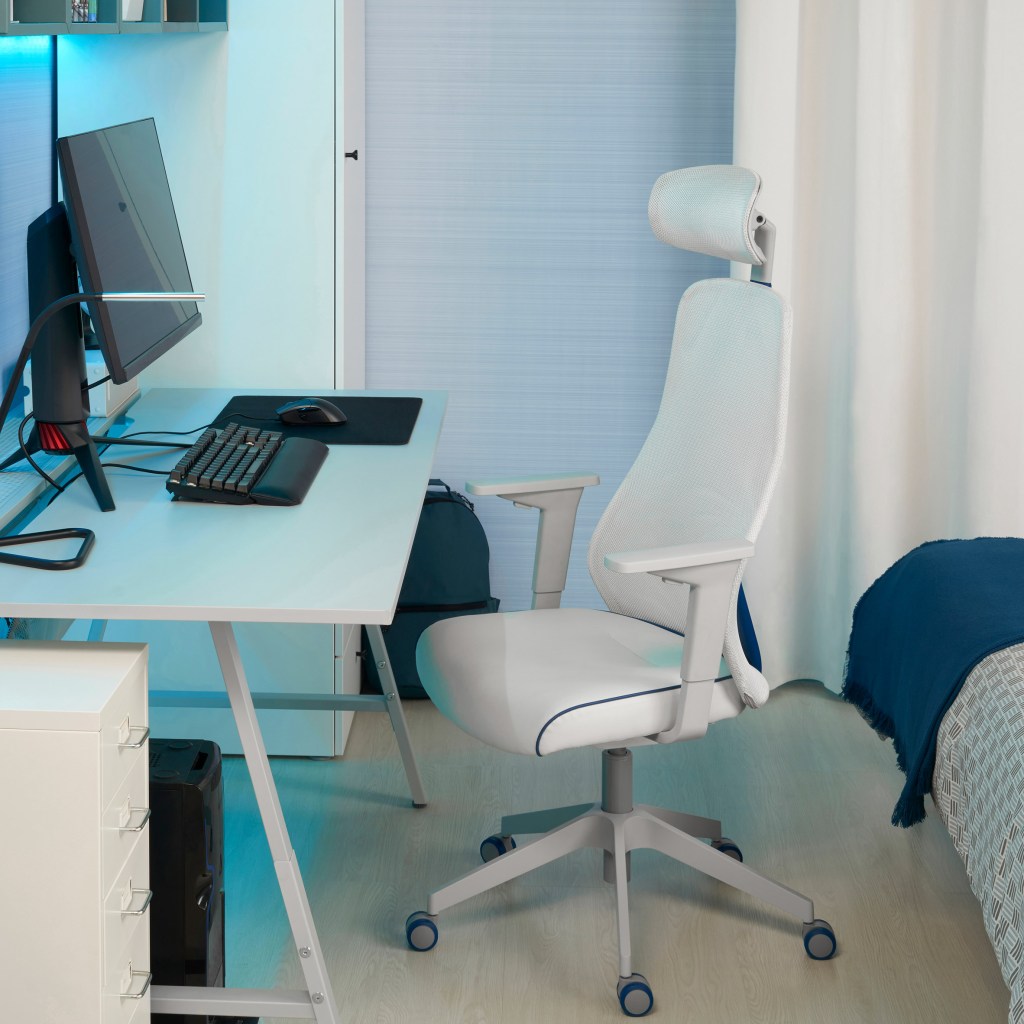 Mesa branca com luzes azul clara, um monitor teclado mouse e mousepad acima dele. Abaixo, do lado esquerdo, a CPU e de frente para ela, uma cadeira branca