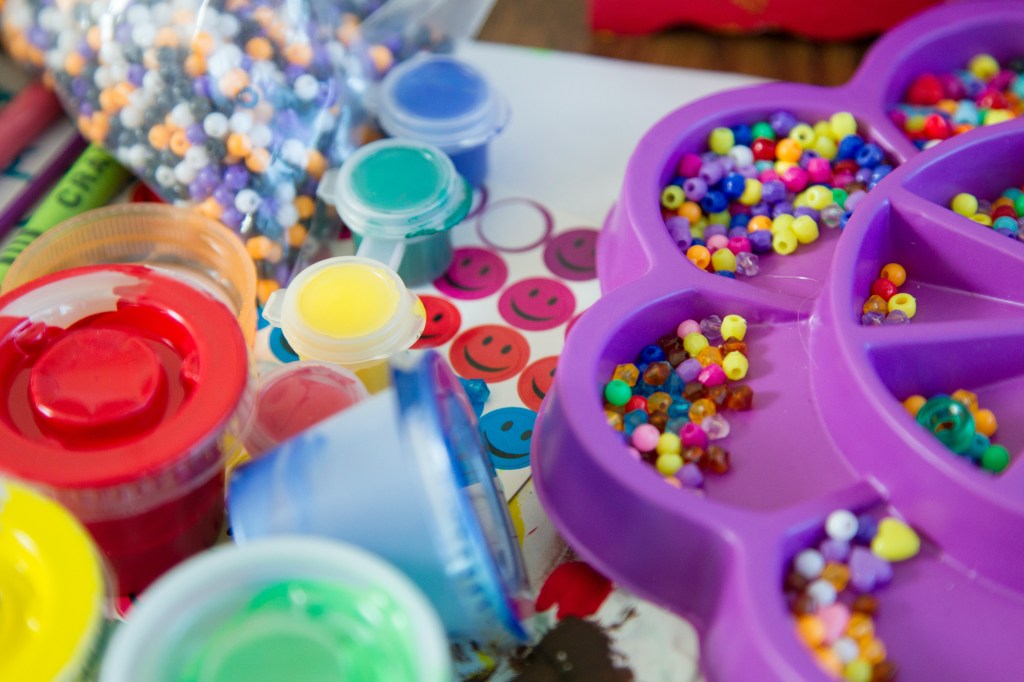 Imagem de mesa com miçangas, linhas, adesivos e miçangas coloridas