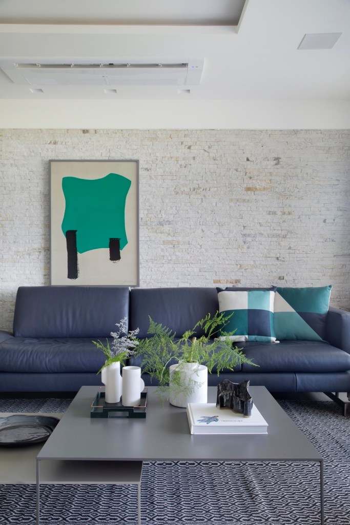 sala de estar com sofá azul e parede de tijolinhos