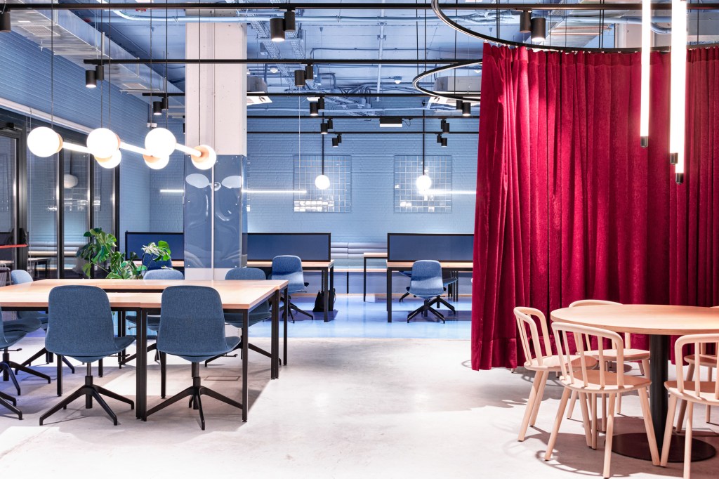 Sala de estudo com paredes azuis e matde do piso na mesma cor, com mesas de madeira e cadeiras azuis