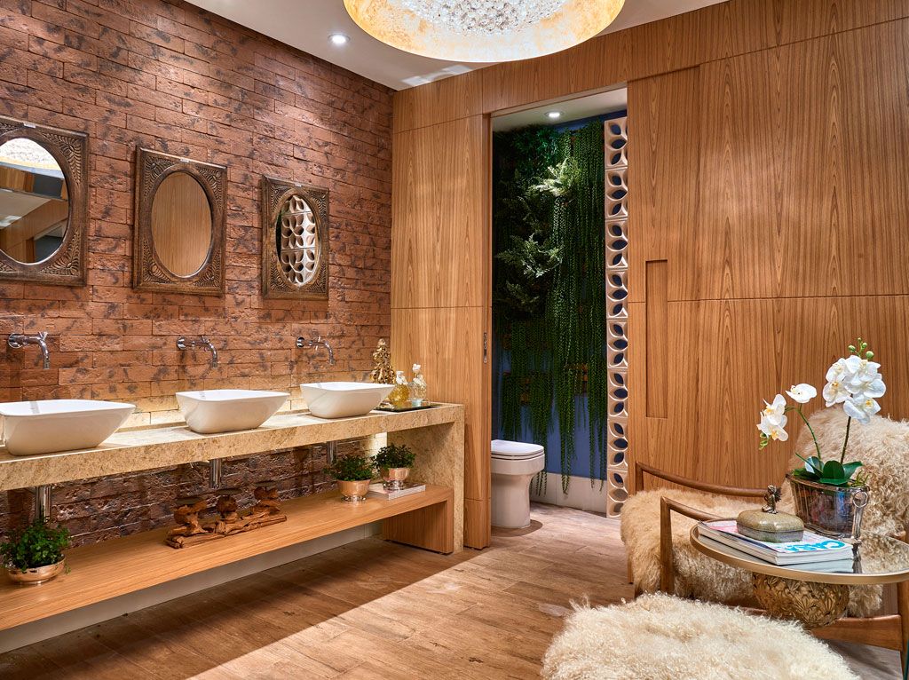 Banheiro em madeira com parede em tijolos. Três espelhos redondos acima de três cubas.