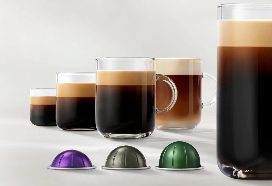 Cinco xícaras de vidro com cafés em diferentes tamanhos. Três cápsulas com diferentes tamanhos