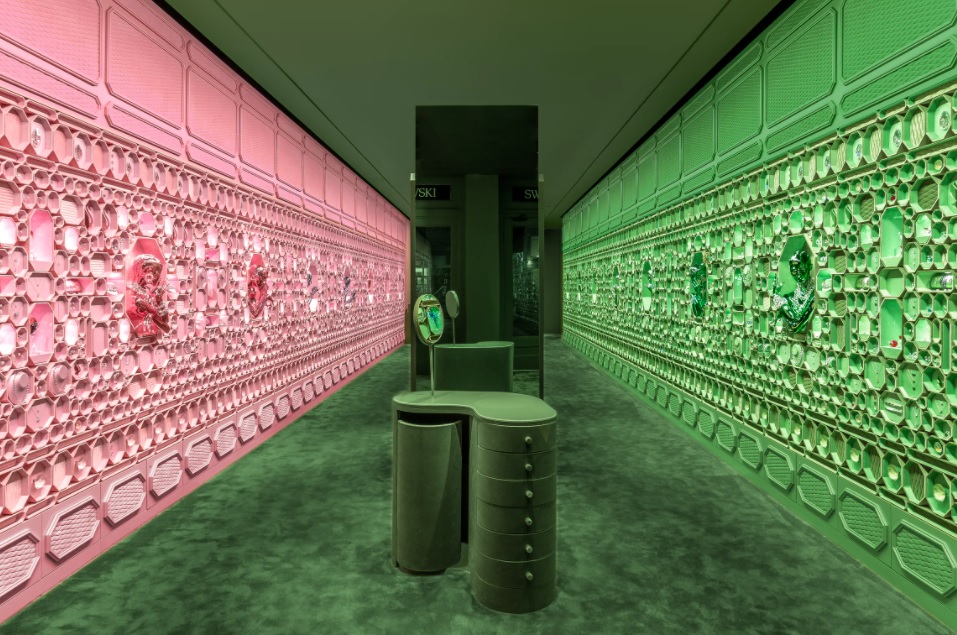 Loja com paredes cobertas por caixinhas octogonais da Swarovski. Parede da esquerda rosa, parede da direita verde.