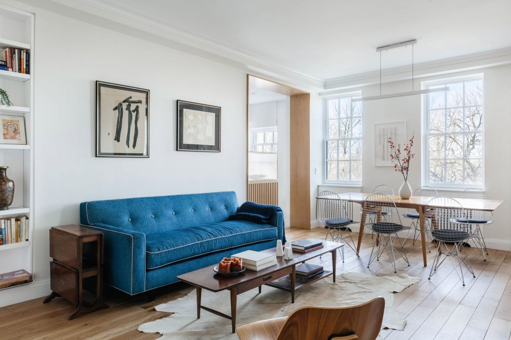 Sala de estar calma com cores claras, piso de madeira e sofá azul