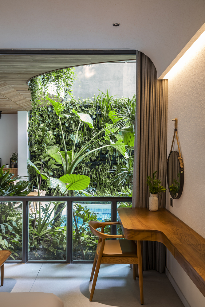 Visão de um das varandas do prédio, com vista para uma vegetação volumosa e também vista para a piscina