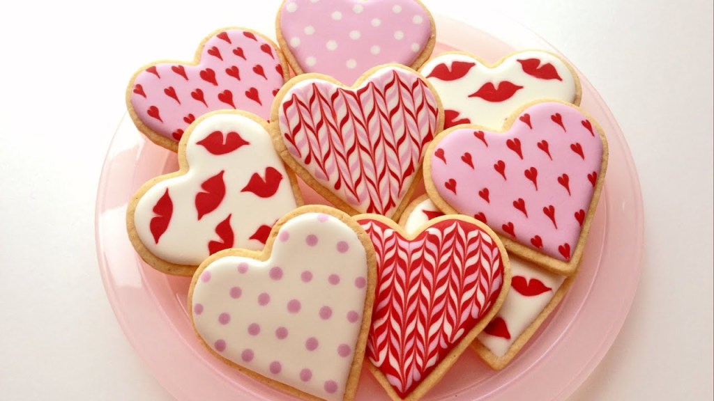 Biscoitos em forma de coração decorados com padrões rosa e vermelhos, corações menores, lábios