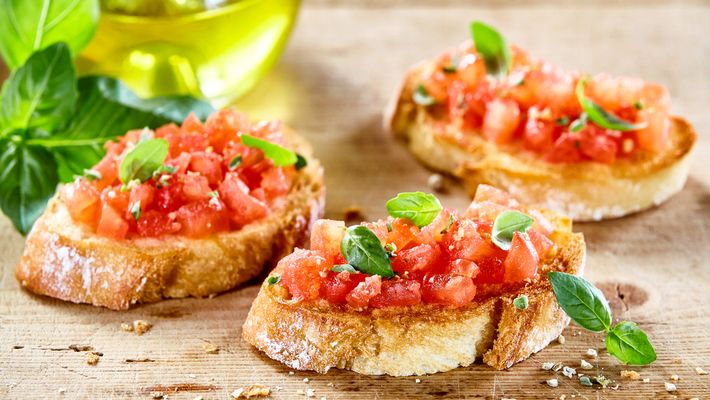 Três fatias de bruschetta em mesa de madeira