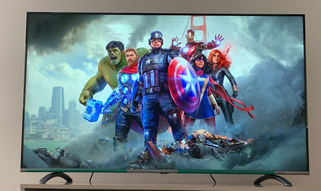 TV Britânia 55" com tela de carregamento do jogo Marvel'Avengers, com personagens do jogo agrupados ao centro