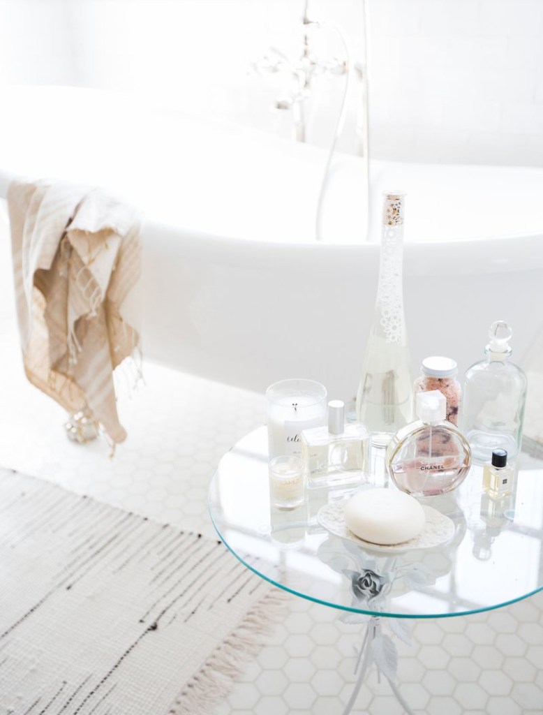 Banheira e mesa lateral de vidro com perfumes