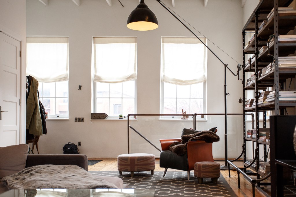 Estilo industrial aplicado em loft com luminária de piso, janelas amplas