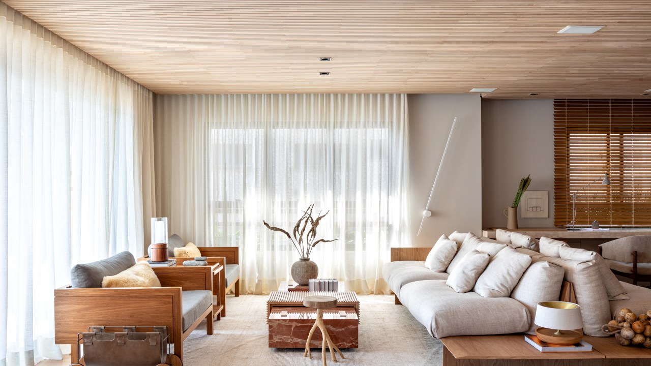 Sala de estar com ripas de madeira clara no teto e décor neutro