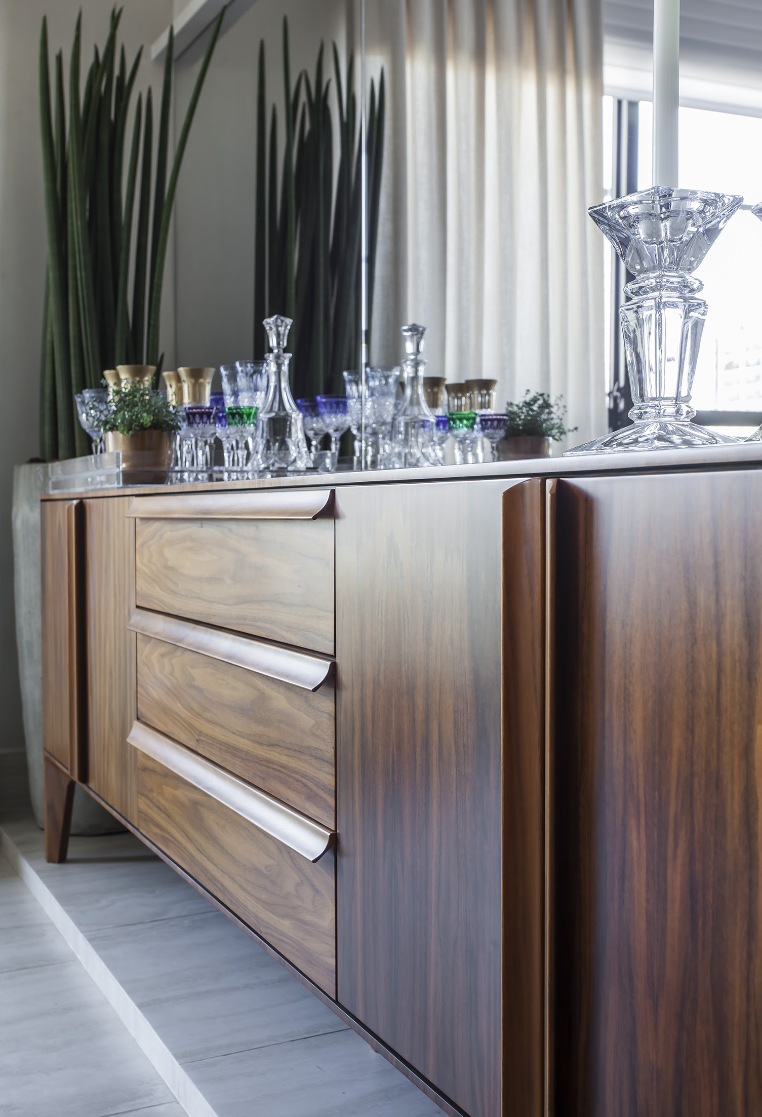 Nesse buffet em madeira Nogueira, um mix entre portas, gavetas e uma grande extens&atilde;o de tampo, que permite a exposi&ccedil;&atilde;o de ta&ccedil;as e outros objetos decorativos