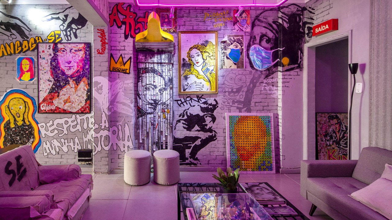Sala de estar com paredes pixadas e quadros encostados na parede e luzes em tons de rosa neon