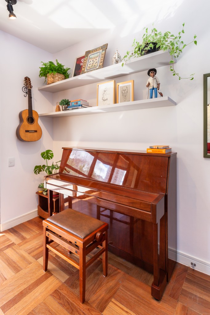 Quarto com piano vertical de madeira clara.