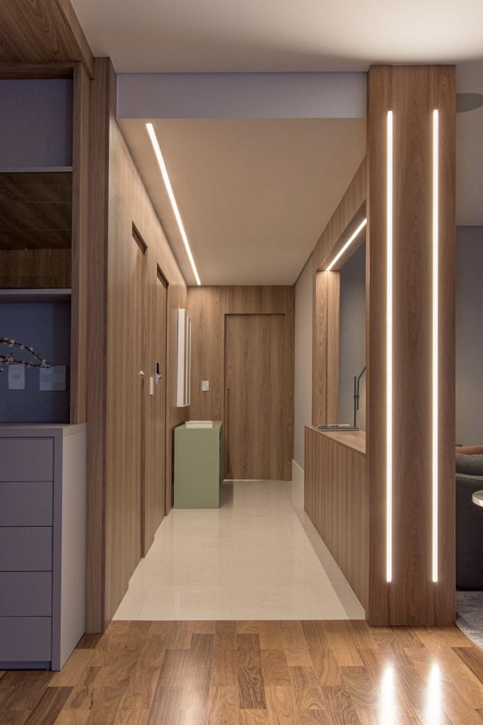 Sala de estar com painéis de madeira que guardam fitas de led que auxiliam na iluminação do ambiente.