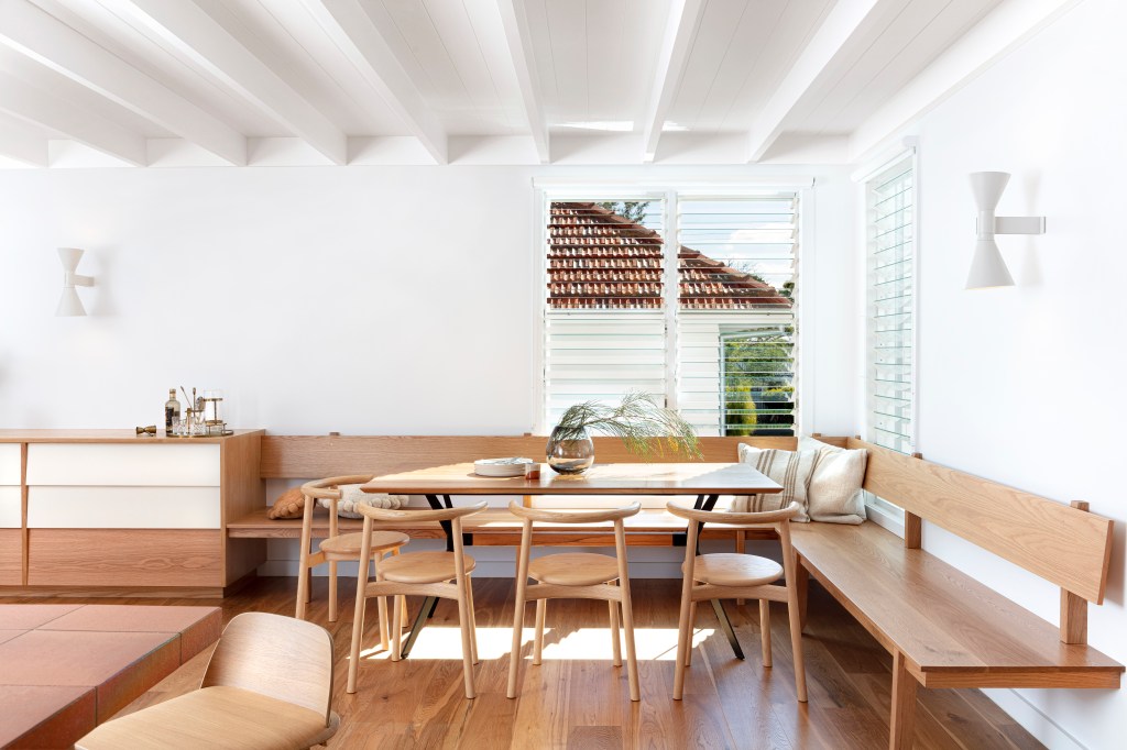 Sala de jantar com bancos de madeira frente à parede branca