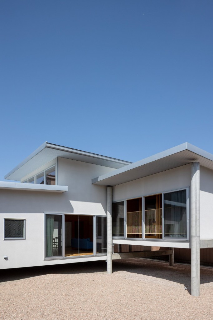 Fachada de casa que fica acima no nível do chão sustentada por palafitas de concreto.