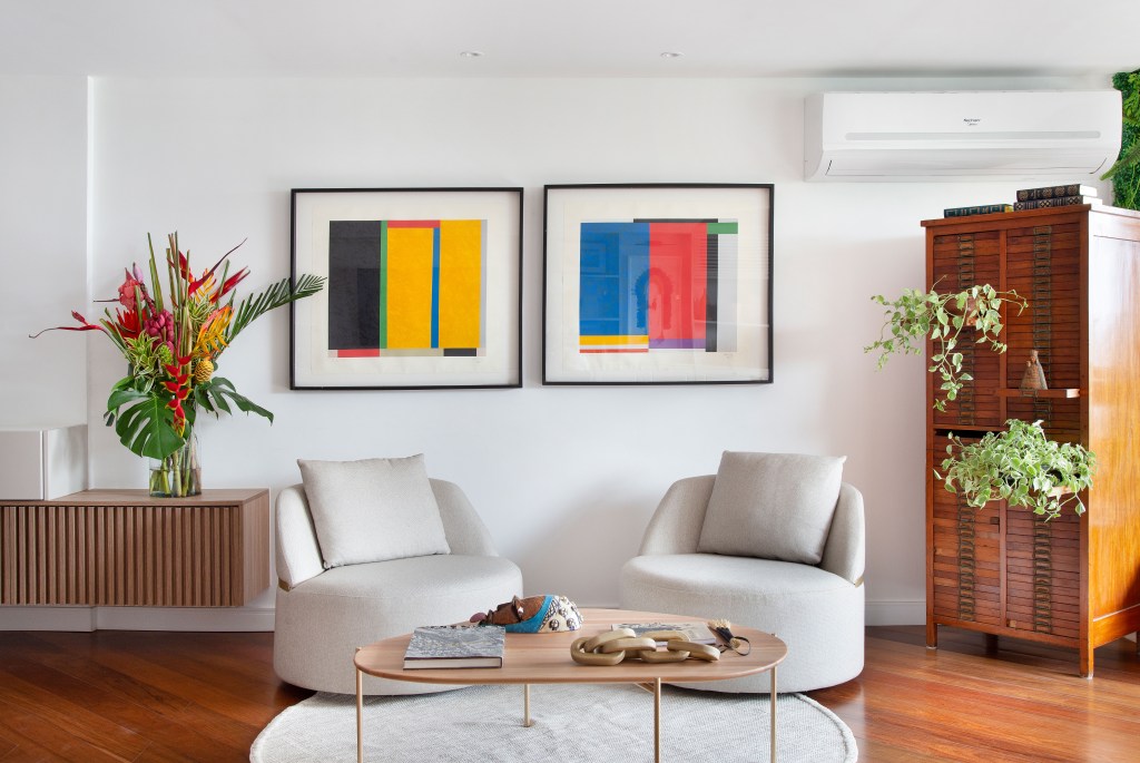Sala de estar com poltronas brancas e quadros coloridos