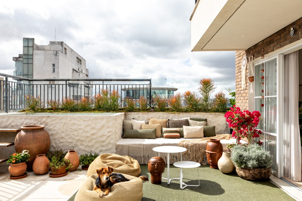 Varanda terraço com pufes, sofá, mesinhas de centro e plantas
