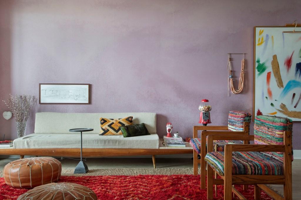 Sala em estilo Boho; sofá branco; parede em rosa queimado e tapete vermelho