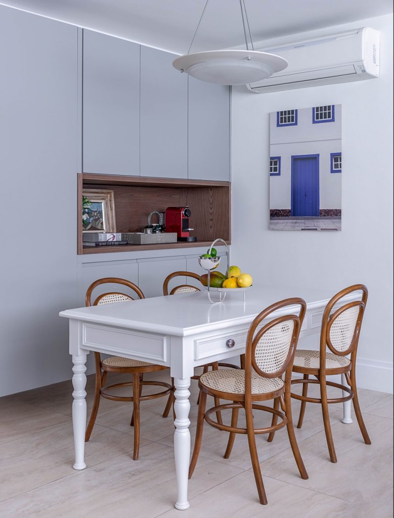 moveis-usados-nova-decoracao4 Cozinha com armários azuis, quatro na parede lateral, mesa branca com quatro cadeiras ao seu redor.