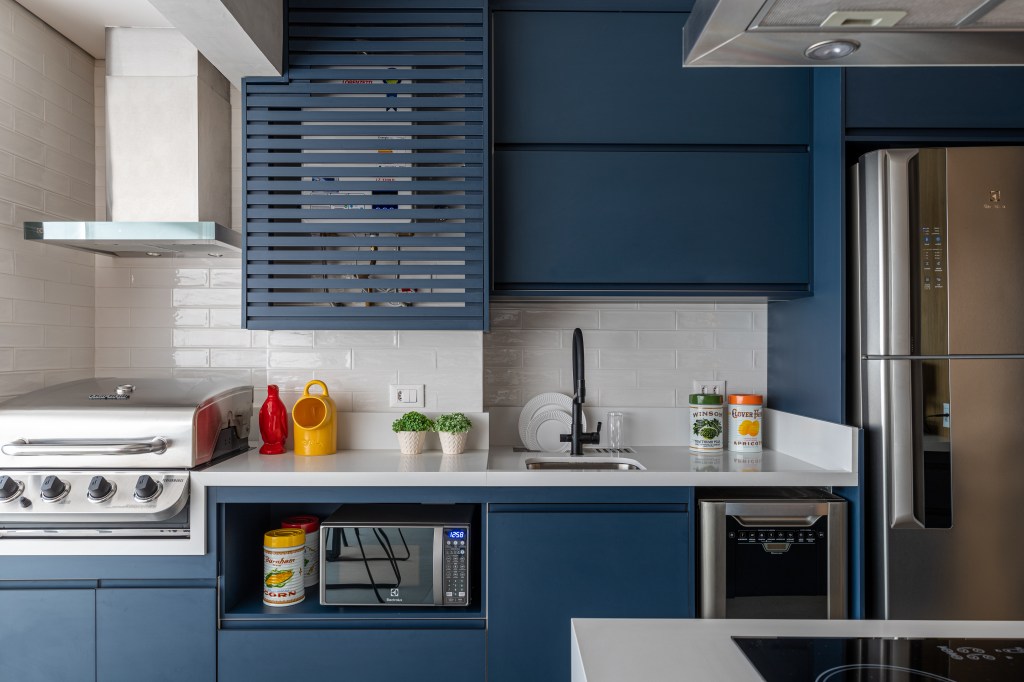 Cozinha americana; cozinha integrada com piso hexagonal, bancada branca e marcenaria azul.