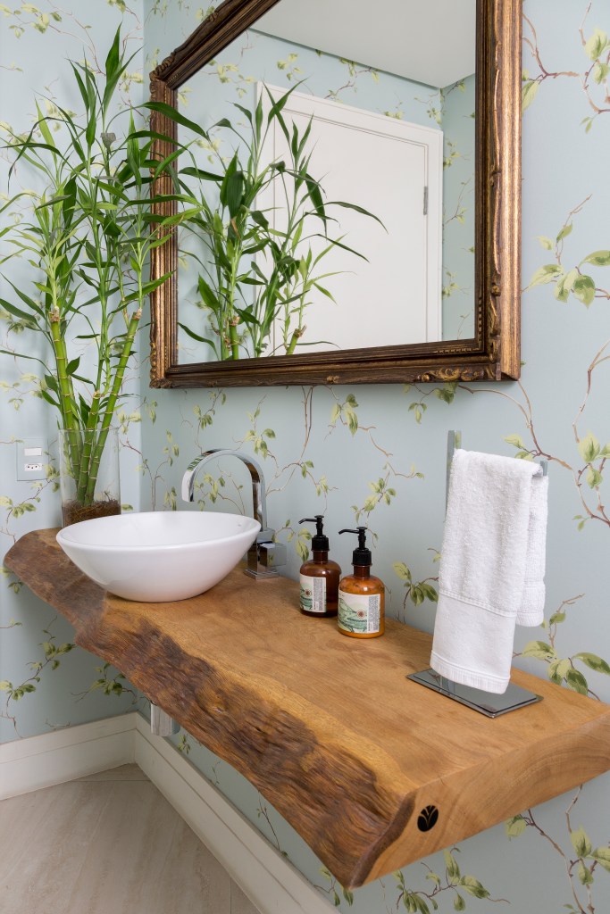 Lavabo com bancada de madeira e papel de parede floral