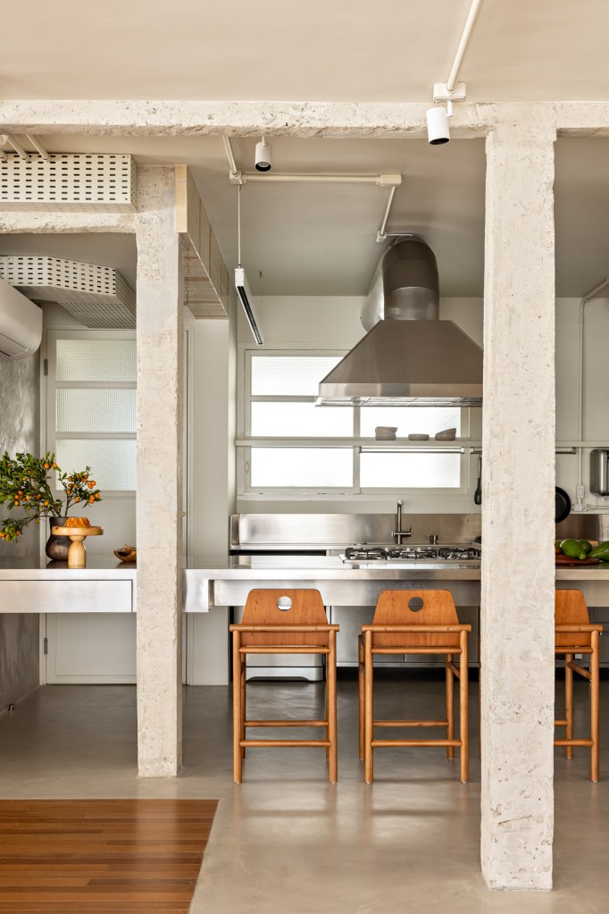 Cozinha integrada em estilo rústico e industrial com ilha, bancada e coifa.