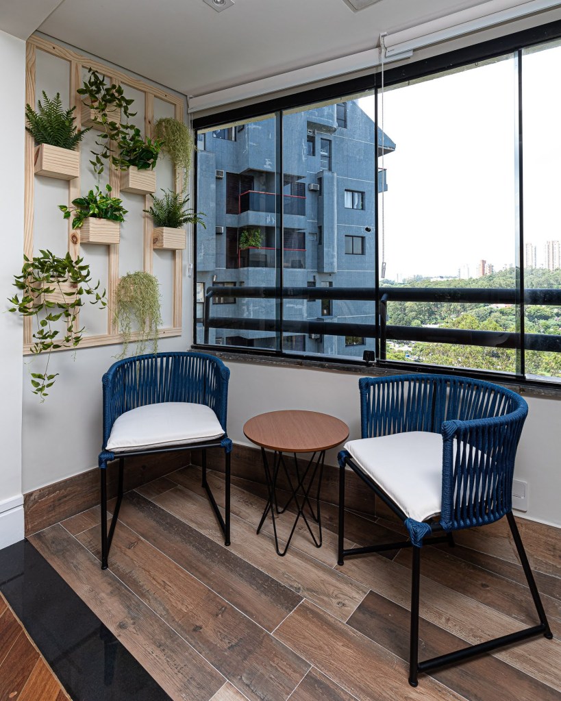 Estilo contemporâneo e industrial marca o décor deste apartamento de 110 m². Projeto Estúdio Wall Arquitetura. Na foto, varanda com jardim vertical a cadeiras de corda azuis.