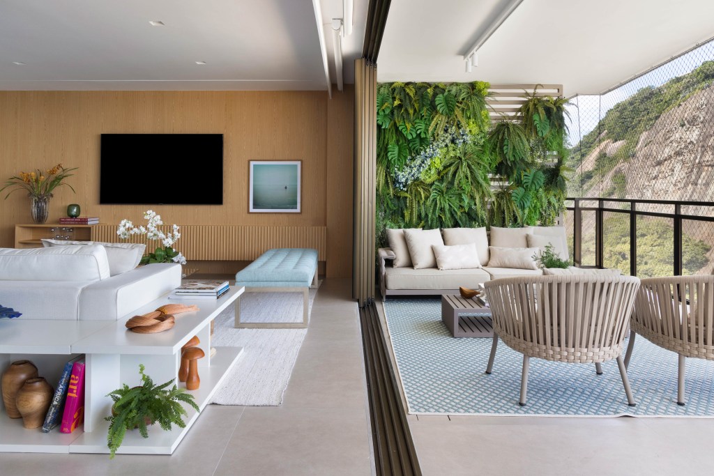 Sala integrada com varanda; piso de porcelanato, sofá branco, jardim vertical.