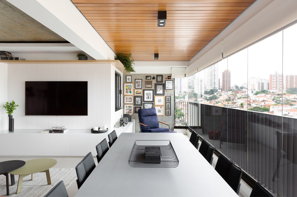 Apê de 142 m² ganha décor neutro que se integra aos eletrodomésticos. Projeto Degradê Arquitetura. Na foto, varanda com gallery wall, mesa e parede ripada.