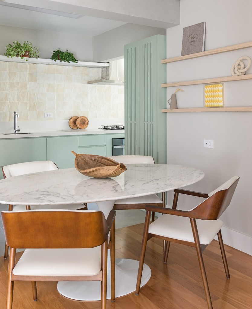 Cozinha verde mint e mesa de trabalho em destaque marcam este apê de 90 m². Projeto Suellen Figueiredo. Na foto, sala de jantar com cozinha integrada e móveis verdes.