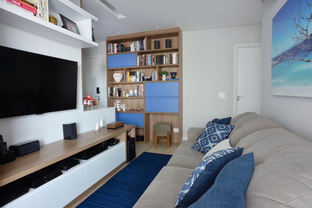 Sala de tv com sofá cinza e estante com nichos