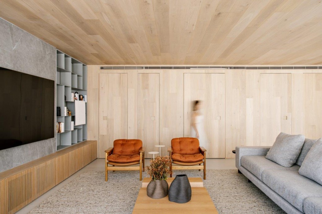 Painéis de madeira revestem o teto e escondem portas neste apê de 220 m²