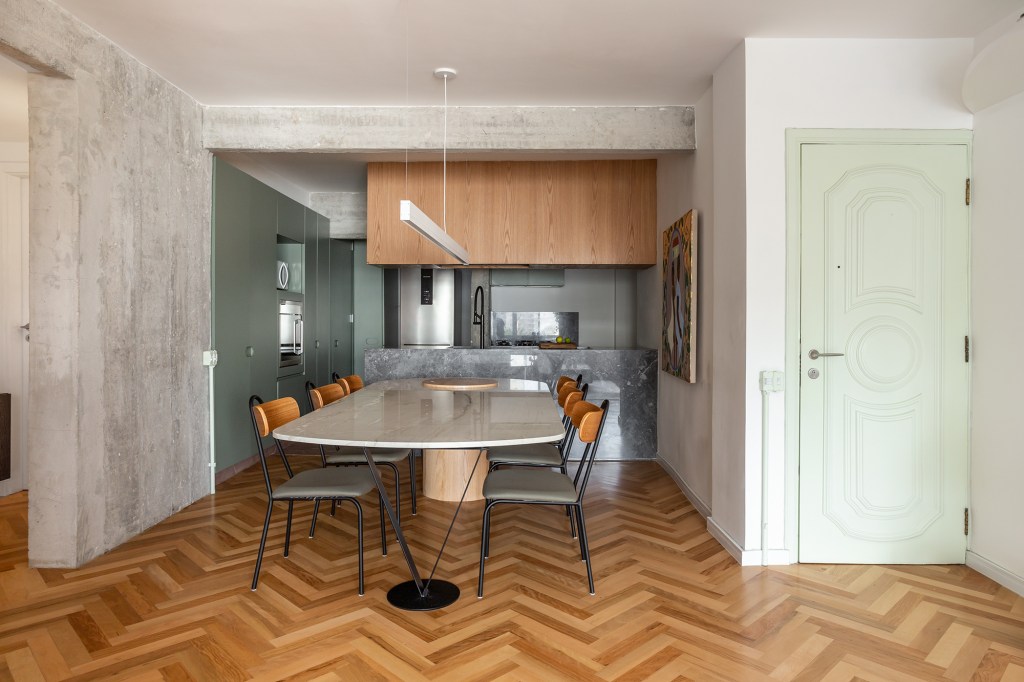 Concreto, verde e rosa marcam o décor deste apê de 110 m². Projeto de MNBR Arquitetos. Na foto, sala de jantar com mesa de pedra, bancada e marcenaria suspensa.