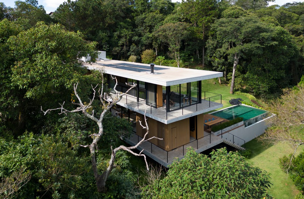 Casa de campo imersa na natureza parece flutuar em meio ao verde. Projeto de Conrado Ceravolo. Na foto, fachada da casa em meio ao jardim. Piscina e varanda.