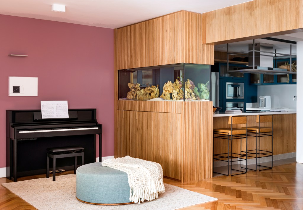 Aquário de peixes funciona como divisória entre sala e cozinha neste apê