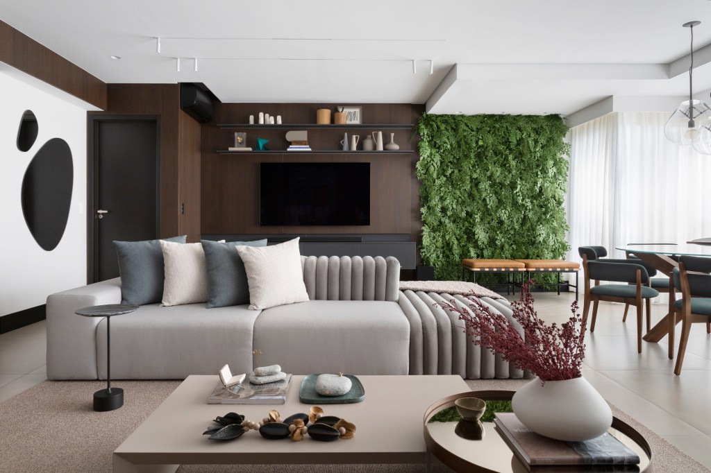 Sofá ilha é ponto central da sala de apê de 135m² com área gourmet