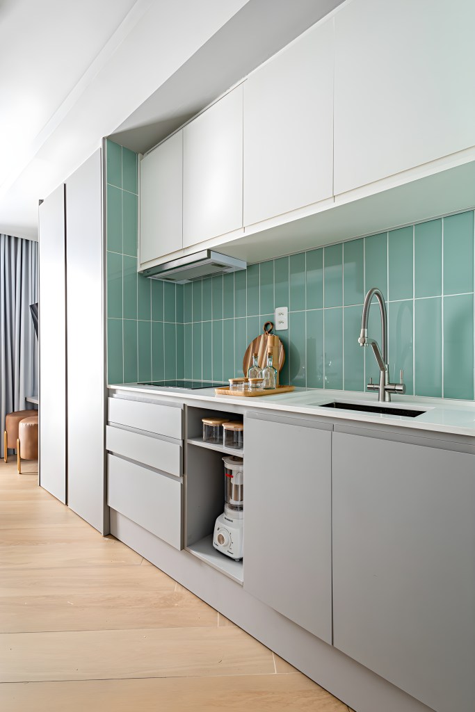 Microapê de 26 m² tem cozinha completa, home office e cantinho de café. Projeto de Go Up Arquitetura. Na foto, cozinha planejada pequena, azulejos azuis, marcenaria cinza.